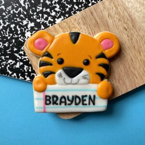 orange and black tiger cookie with the name Brayden on a blue, black, and white background